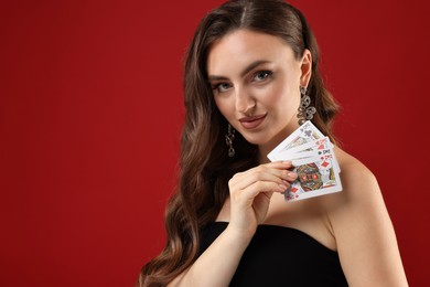 Photo of Poker game. Charming woman with playing cards on red background. Space for text