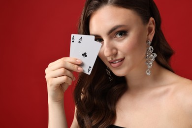 Poker game. Charming woman with playing cards on red background