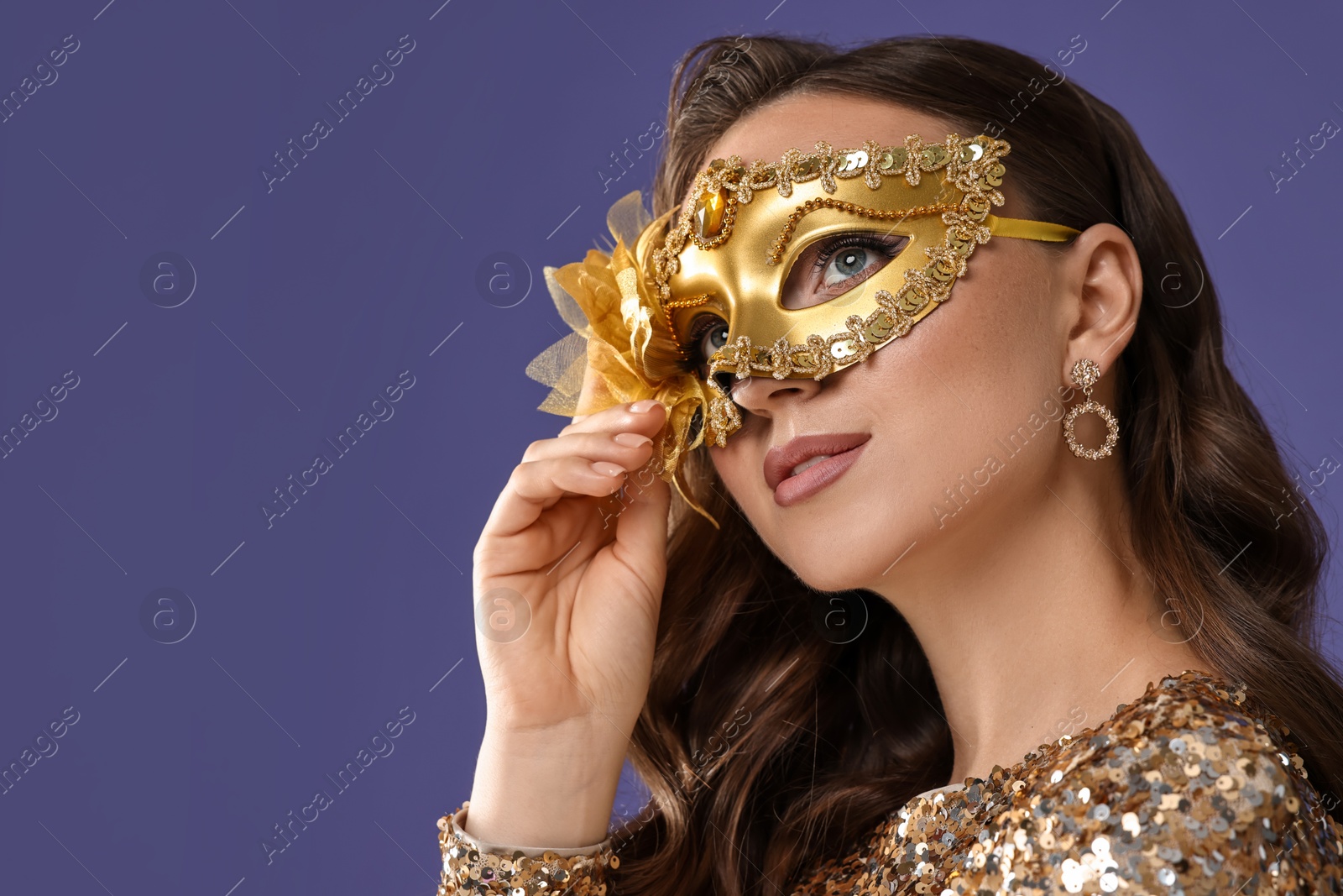 Photo of Beautiful woman wearing carnival mask on purple background, closeup. Space for text