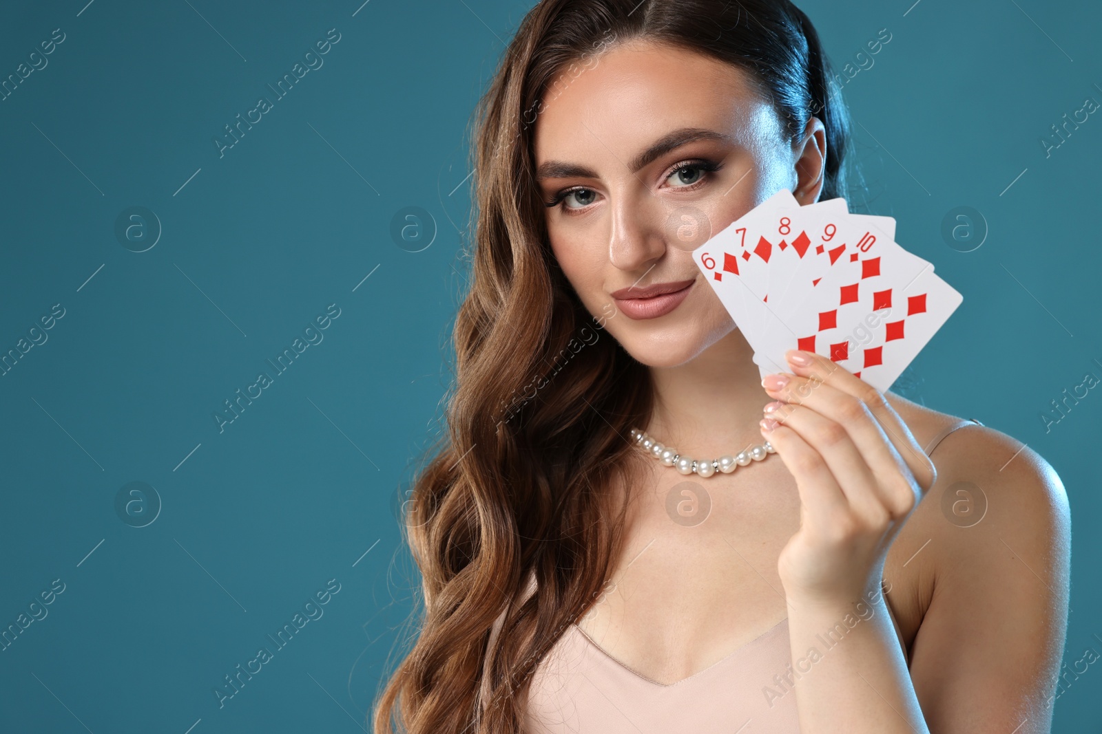 Photo of Poker game. Charming woman with playing cards on light blue background. Space for text