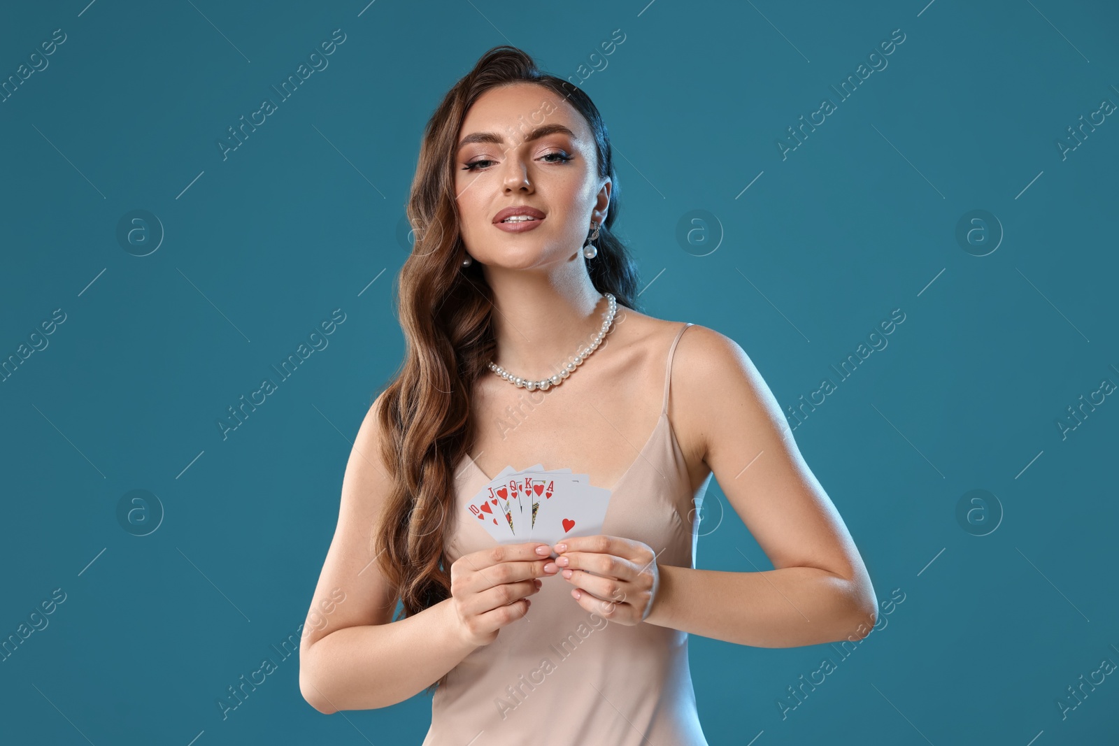 Photo of Poker game. Charming woman with playing cards on light blue background