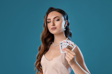 Poker game. Charming woman with playing cards on light blue background