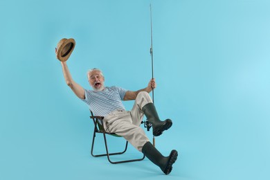 Fisherman with rod on fishing chair against light blue background