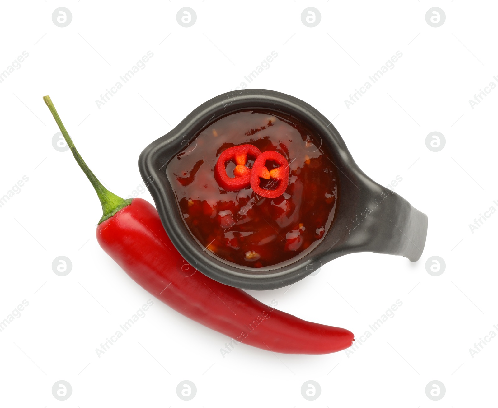 Photo of Hot chili sauce in gravy boat and pepper isolated on white, top view