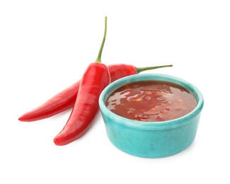 Photo of Hot chili sauce in bowl and peppers isolated on white