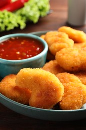 Photo of Plate with hot chili sauce and nuggets on table, closeup