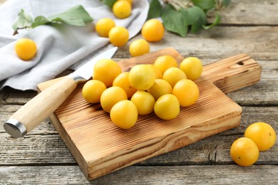 Photo of Whole and cut ripe plums with knife on wooden table