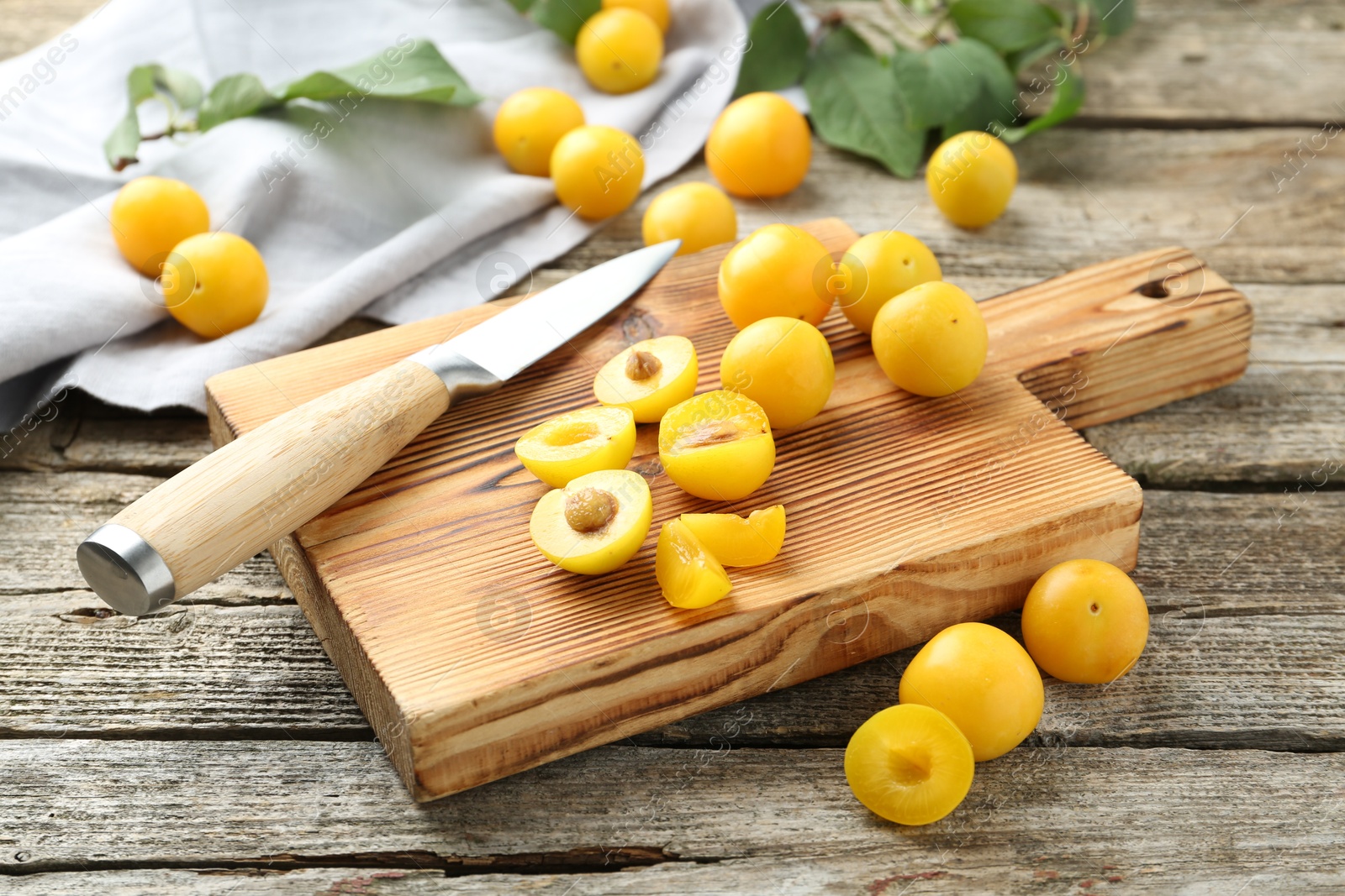 Photo of Whole and cut ripe plums with knife on wooden table