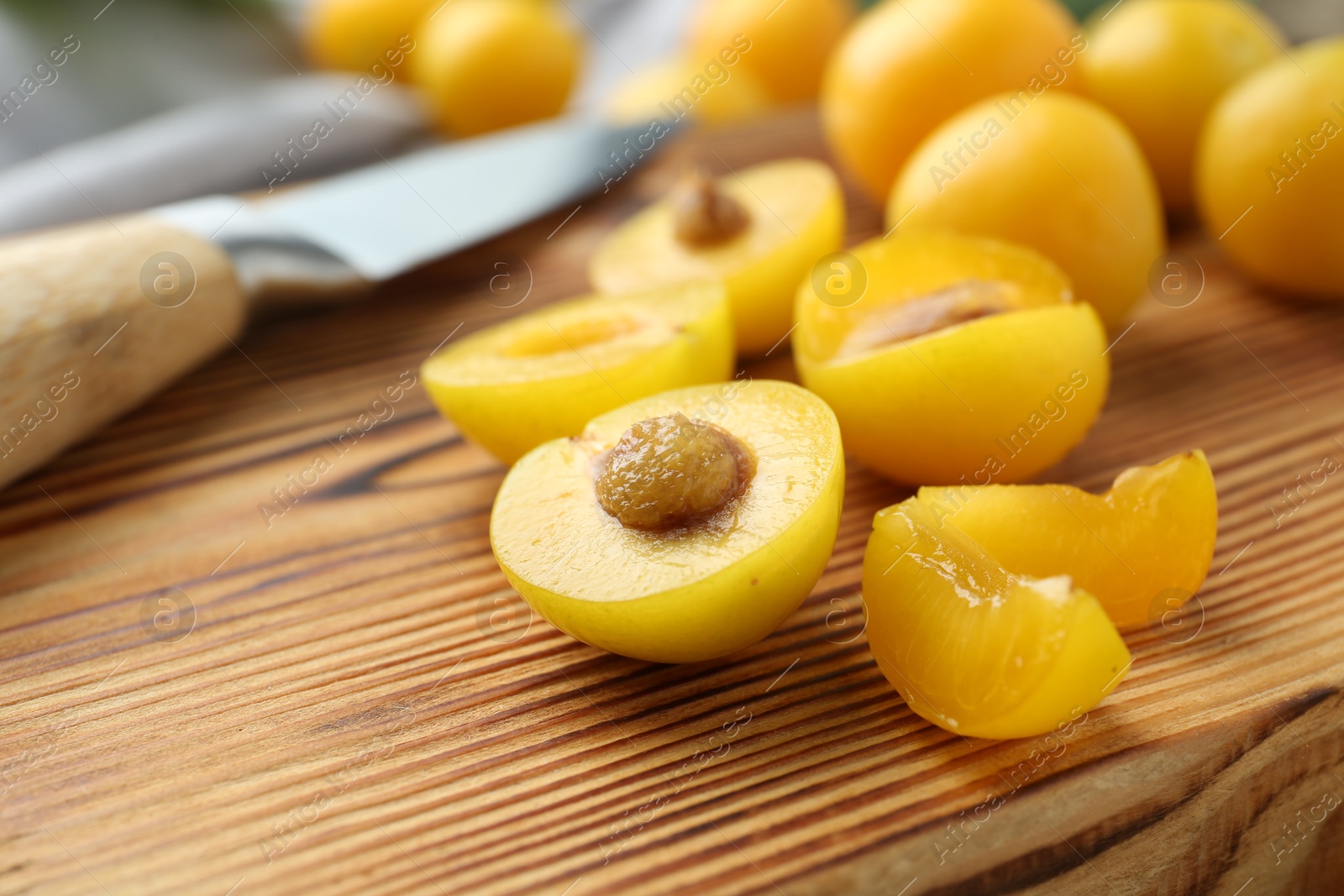 Photo of Whole and cut ripe plums on wooden table, closeup