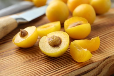 Photo of Whole and cut ripe plums on wooden table, closeup