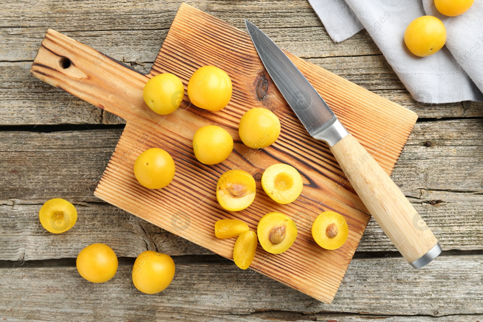 Photo of Whole and cut ripe plums with knife on wooden table, flat lay