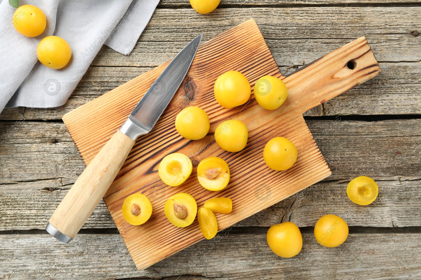 Photo of Whole and cut ripe plums with knife on wooden table, flat lay