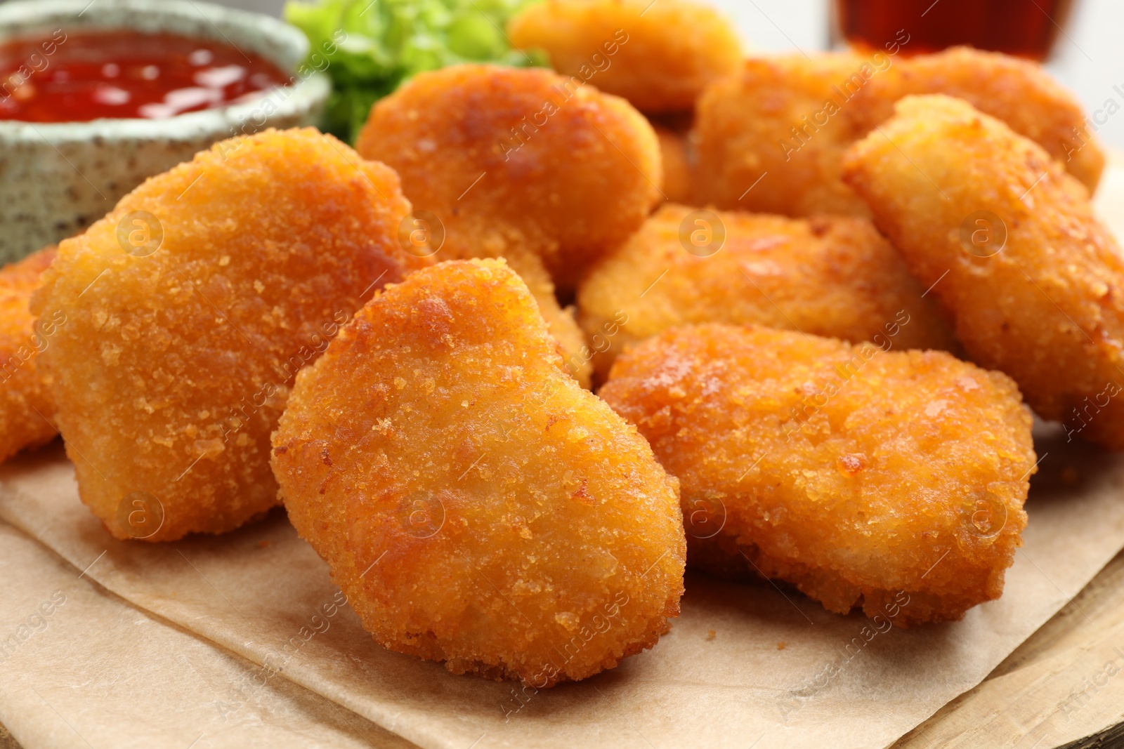 Photo of Tasty nuggets and hot chili sauce on parchment, closeup