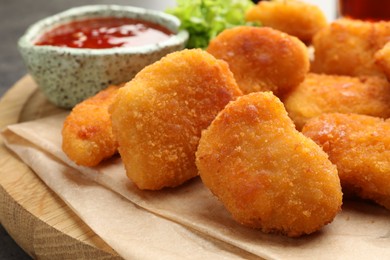 Photo of Board with nuggets and hot chili sauce on table, closeup