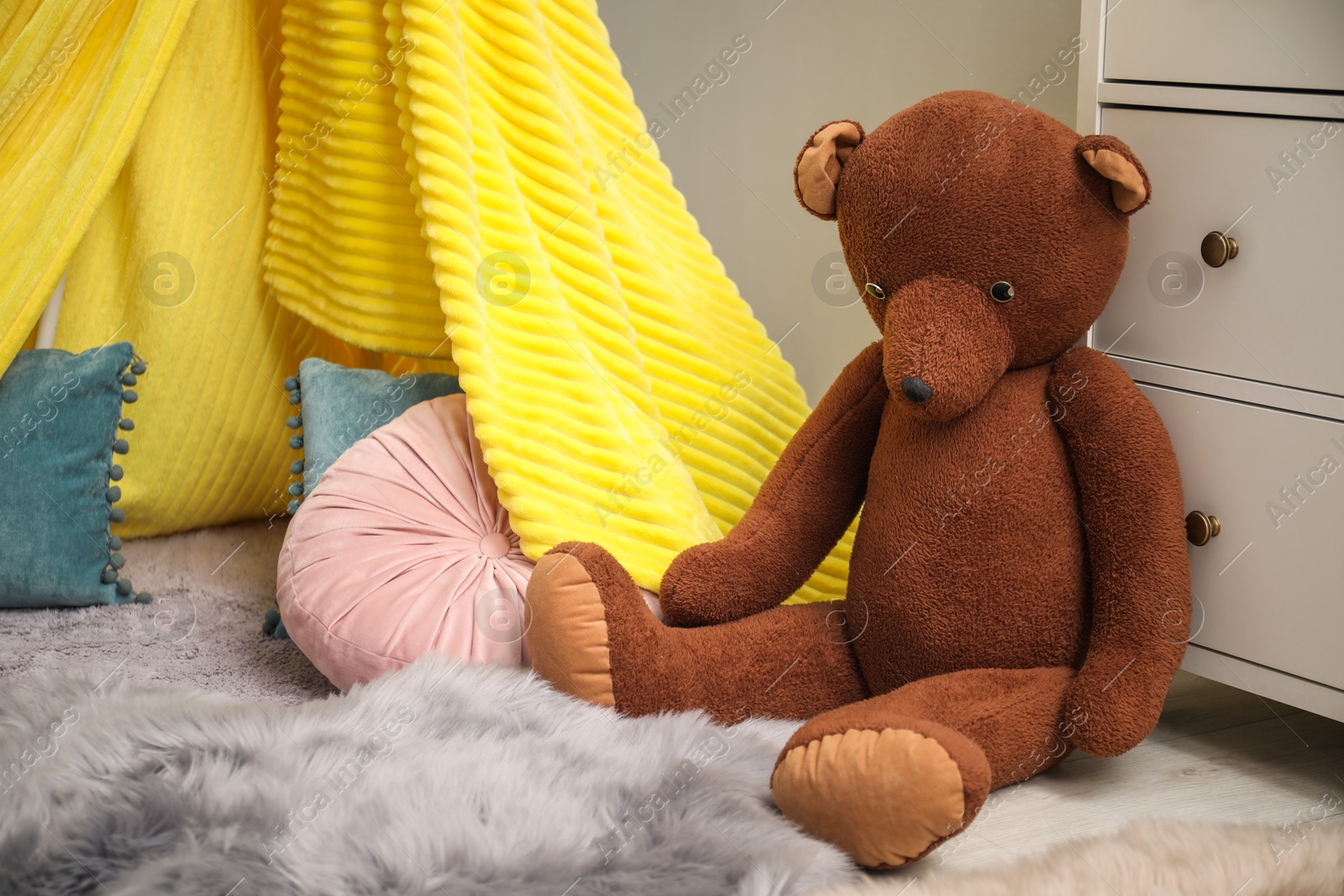 Photo of Play tent, pillows and toy bear in child room. Interior design