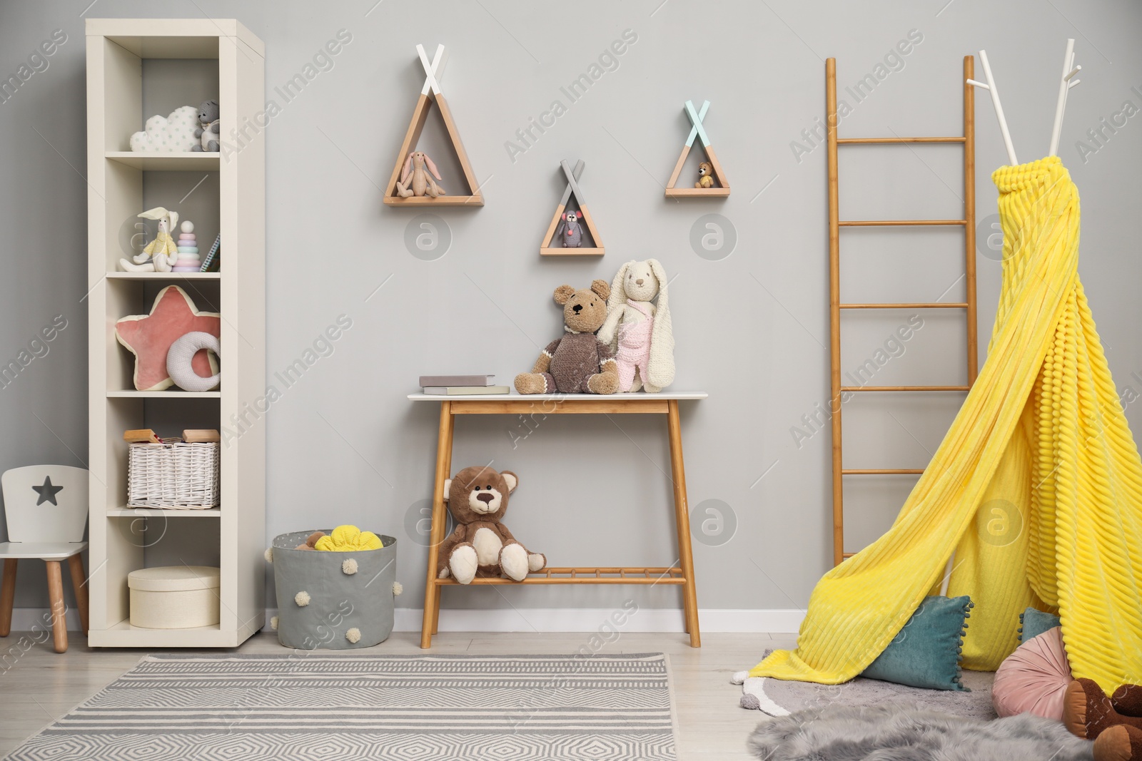 Photo of Stylish child room interior with modern furniture, toys and play tent