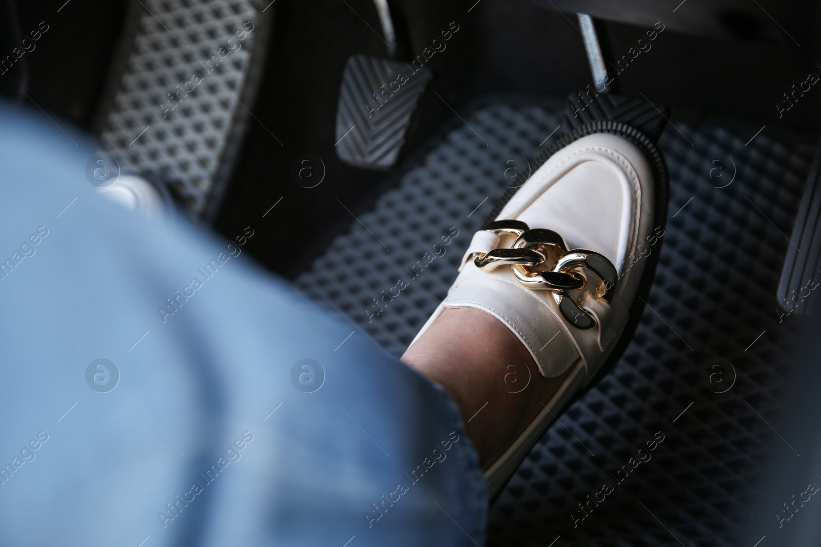 Photo of Woman in white shoes pushing on pedal of car brake, closeup