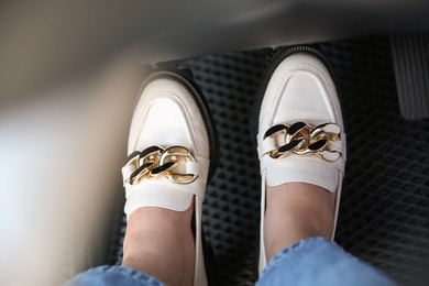 Photo of Woman in white shoes pushing on pedal of car brake, closeup