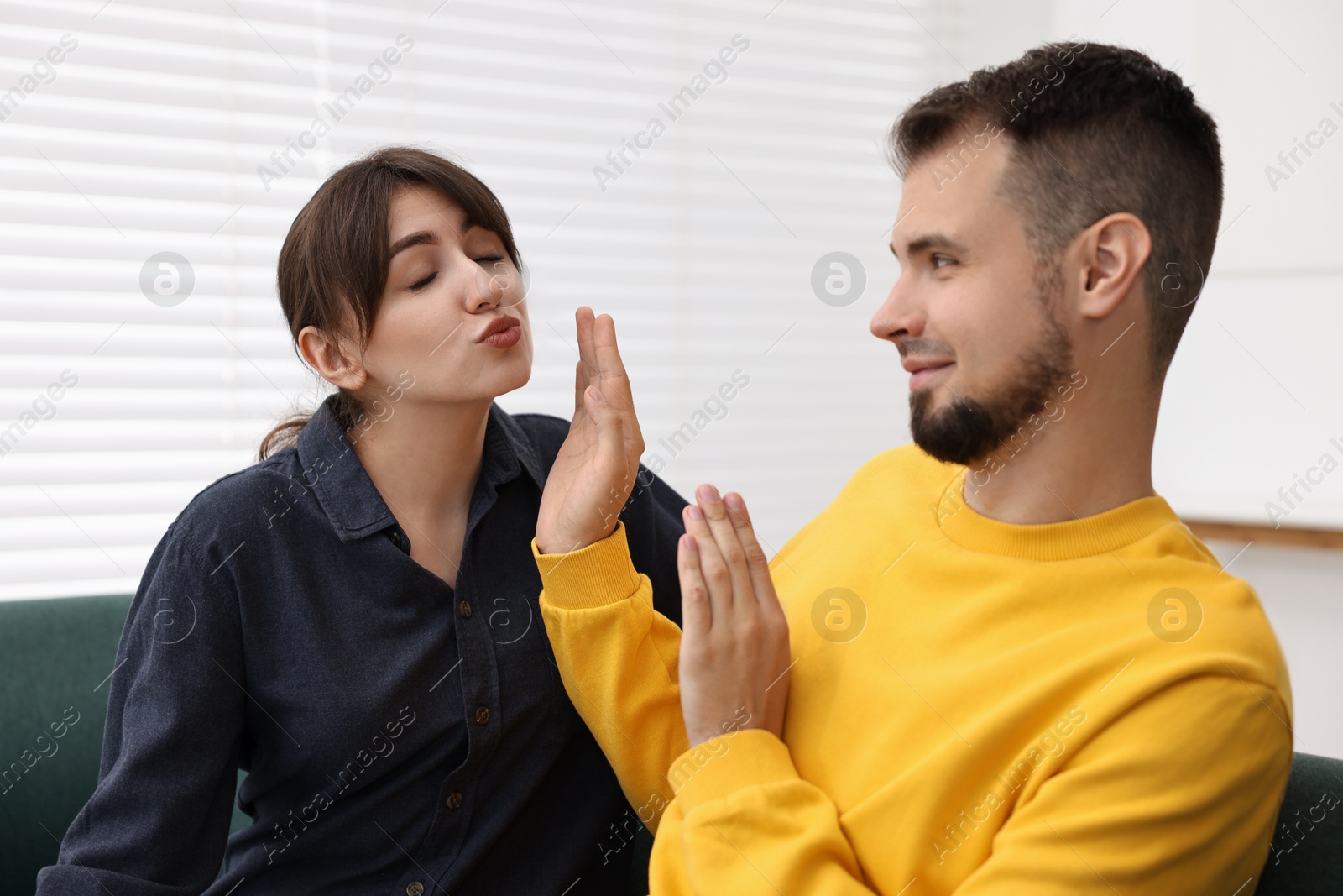 Photo of Embarrassed man refusing from woman's kiss at home