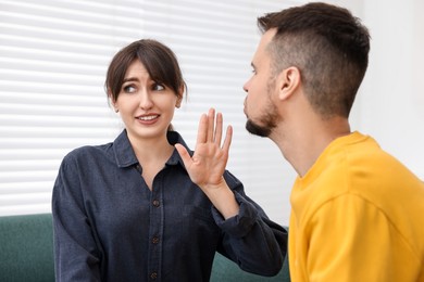 Embarrassed woman refusing from man's kiss at home