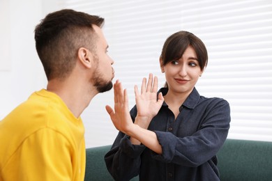 Embarrassed woman refusing from man's kiss at home