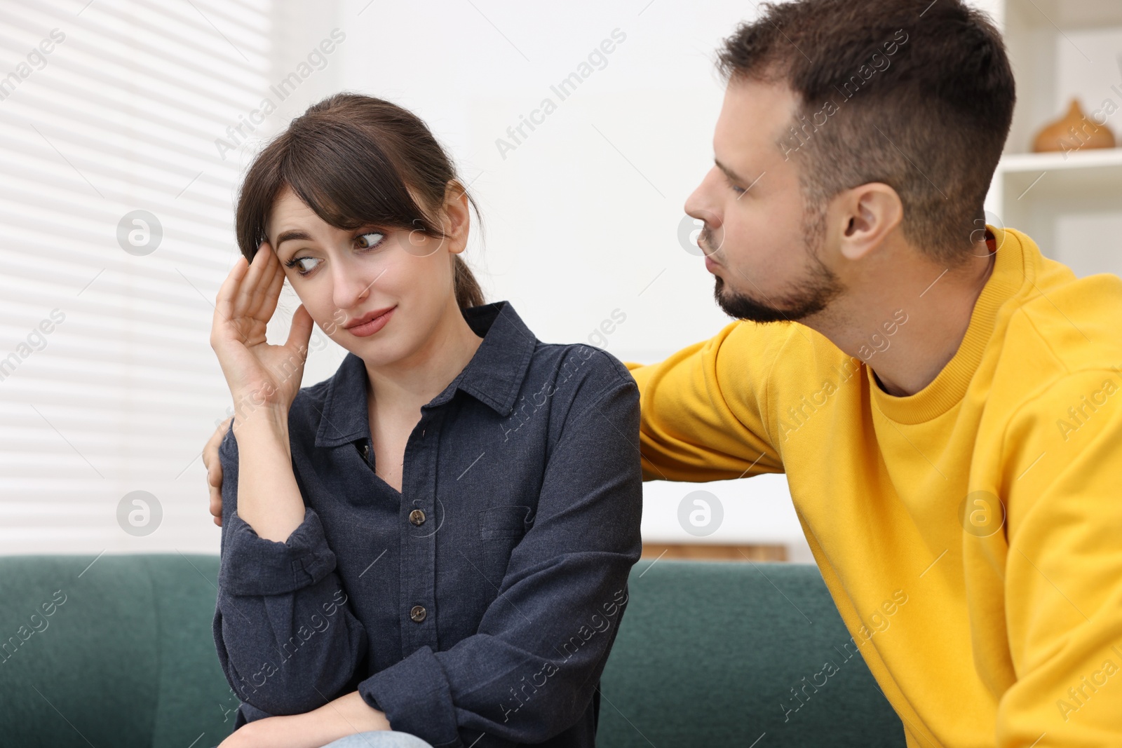 Photo of Man trying to kiss embarrassed woman at home