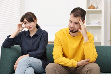 Embarrassed couple ignoring each other on sofa at home