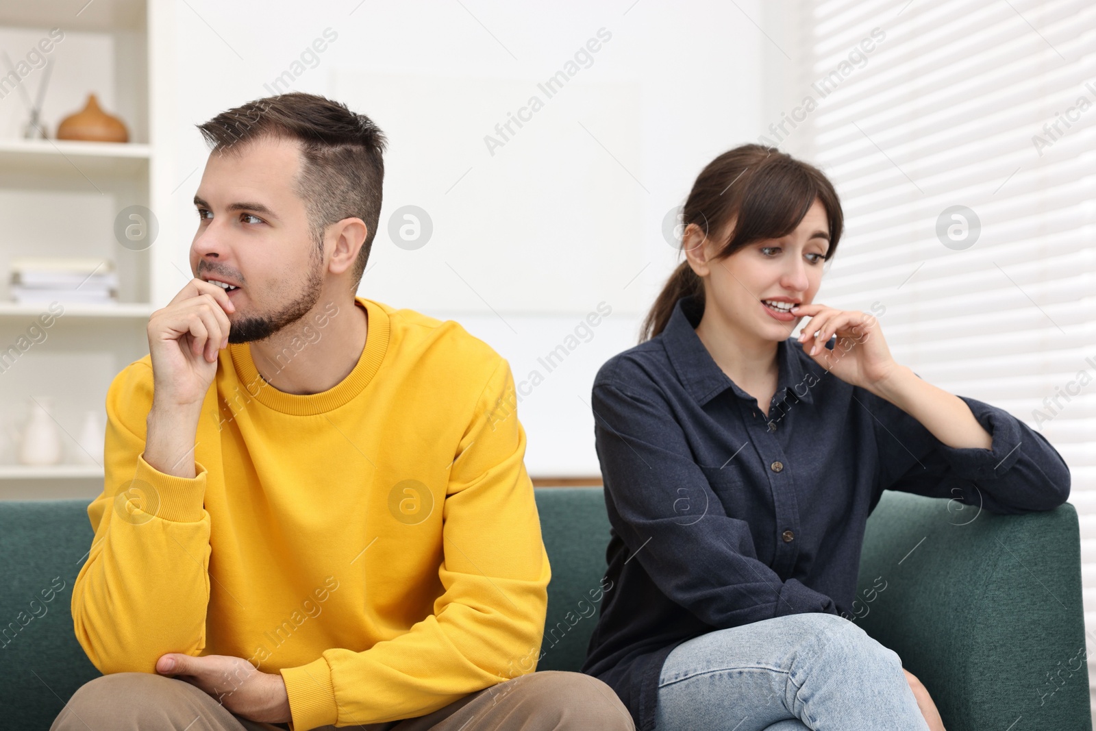 Photo of Embarrassed couple ignoring each other on sofa at home