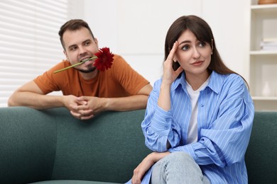 Man with flower in mouth flirting with embarrassed woman at home