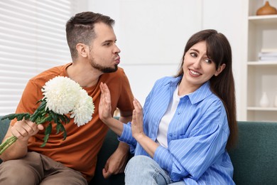 Embarrassed woman refusing from man's kiss at home