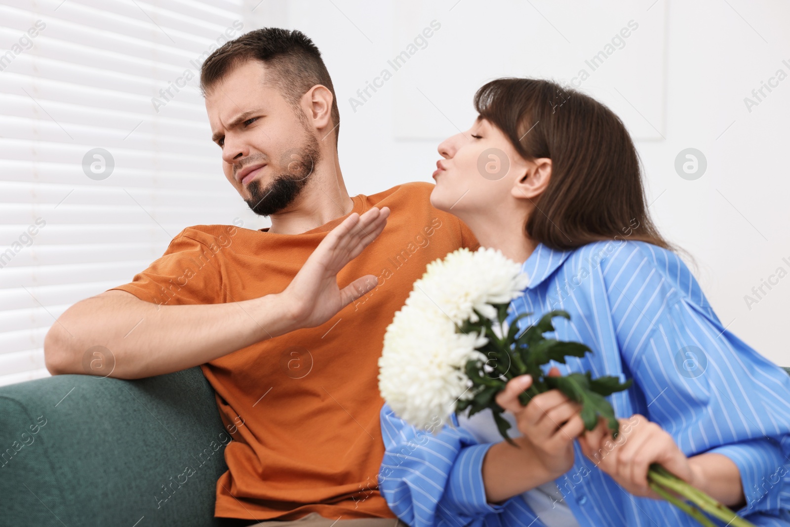 Photo of Embarrassed man refusing from woman's kiss at home