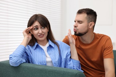 Embarrassed woman refusing from man's kiss at home