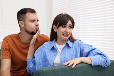 Embarrassed woman refusing from man's kiss at home