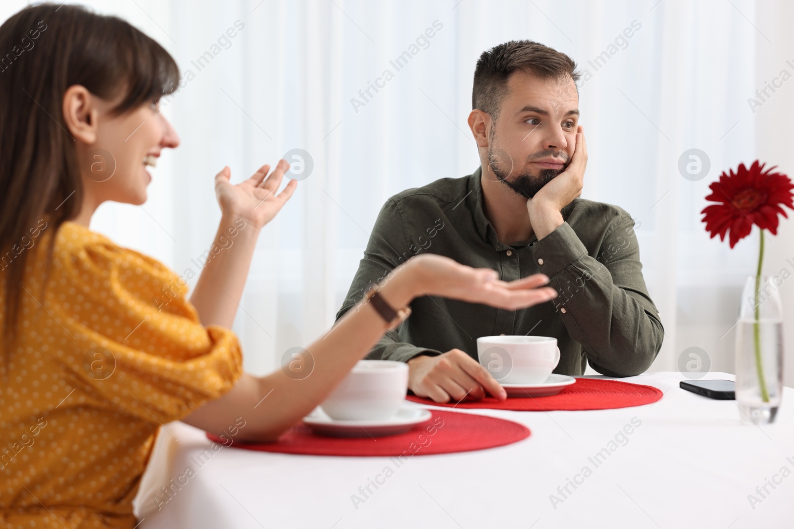 Photo of Bad date. Obsessive woman talking to embarrassed man at table indoors