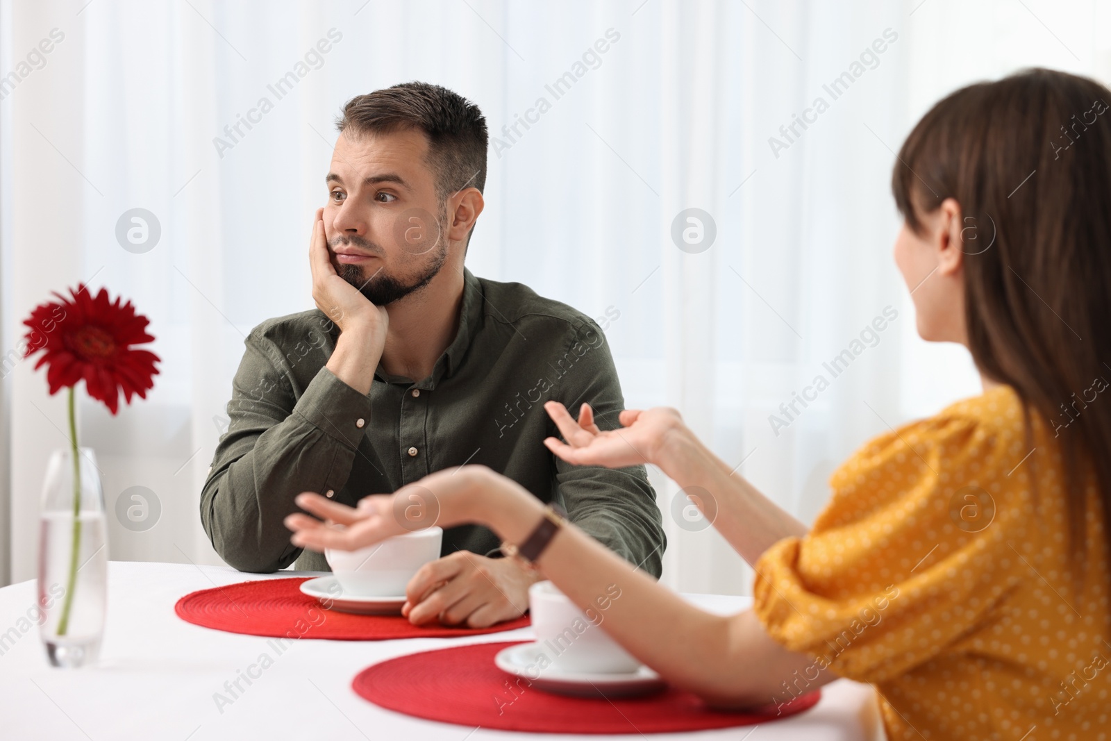 Photo of Bad date. Obsessive woman talking to embarrassed man at table indoors