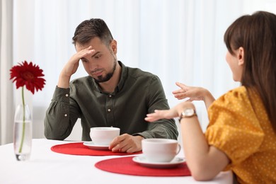 Photo of Bad date. Obsessive woman talking to embarrassed man at table indoors