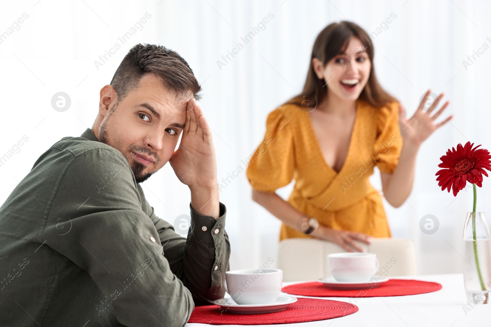 Photo of Bad date. Embarrassed man ignoring smiling woman indoors, selective focus