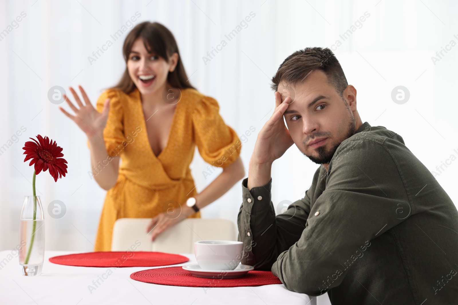 Photo of Bad date. Embarrassed man ignoring smiling woman indoors, selective focus