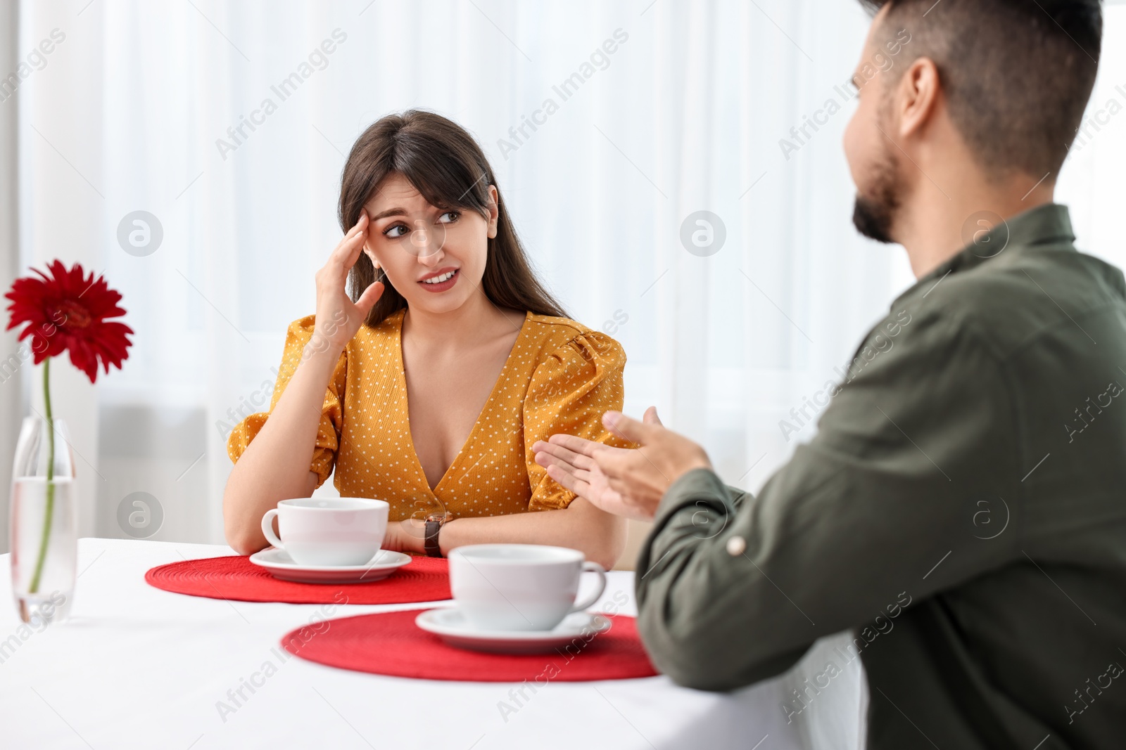 Photo of Bad date. Obsessive man talking to embarrassed woman at table indoors