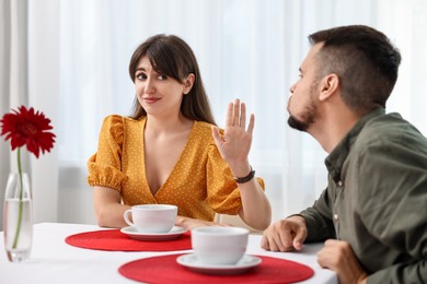 Bad date. Embarrassed woman refusing from man's kiss indoors