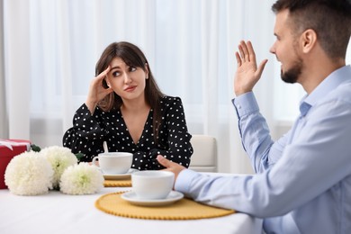 Embarrassing date. Obsessive man talking to bored woman at table indoors