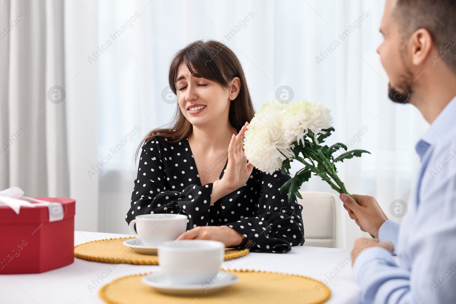 Photo of Bad date. Embarrassed woman refusing from man's flowers indoors