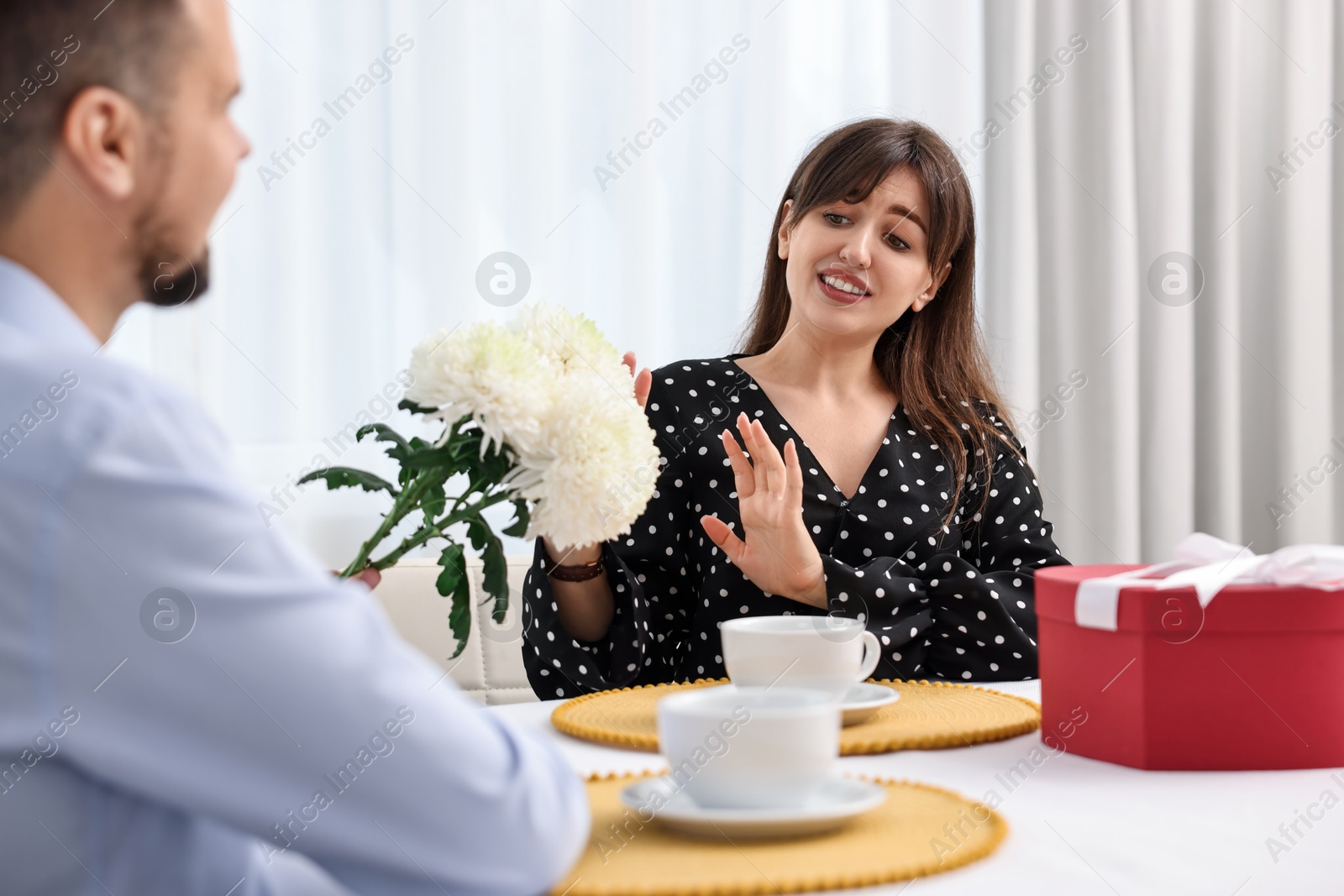 Photo of Bad date. Embarrassed woman refusing from man's flowers indoors