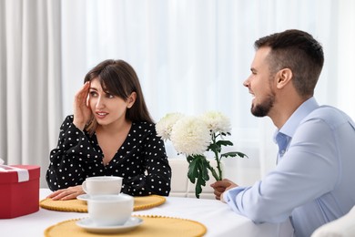 Photo of Bad date. Embarrassed woman ignoring man with flowers indoors