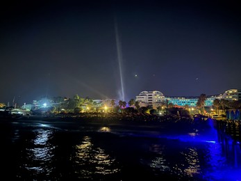 Photo of Beautiful view of night cityscape with sea and illuminated buildings