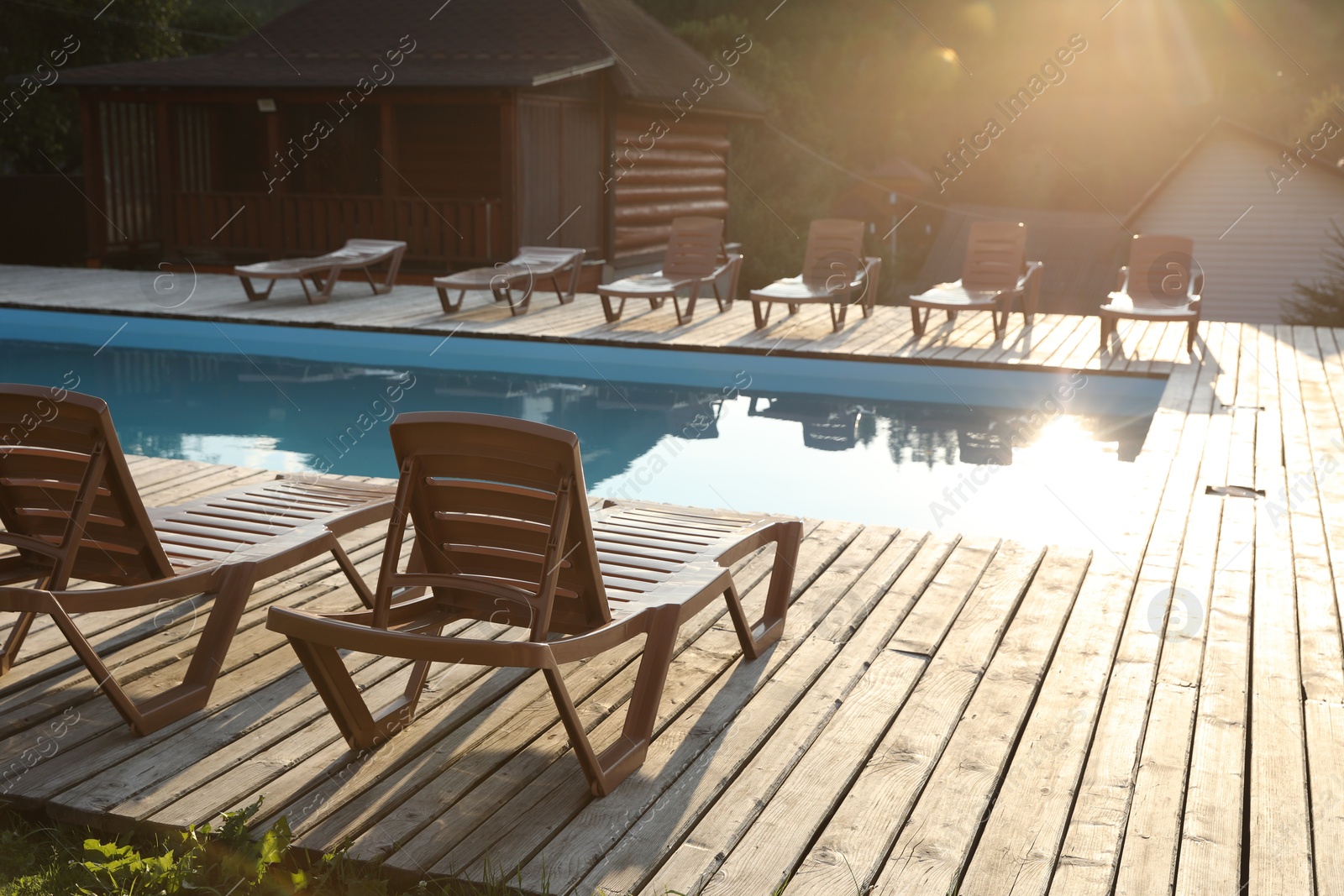 Photo of Outdoor swimming pool, sunbeds and houses on sunny day