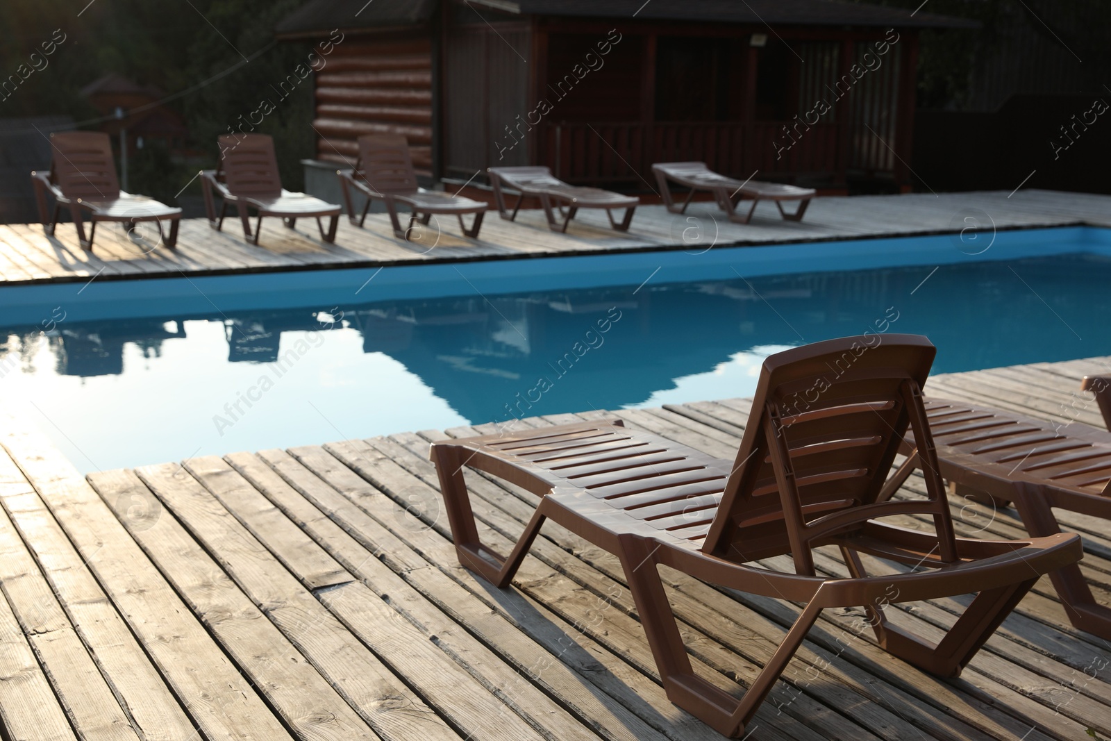 Photo of Outdoor swimming pool with clear water, sunbeds and house