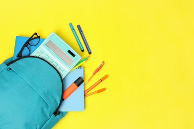 Photo of Light blue backpack and different school supplies on yellow background, flat lay. Space for text