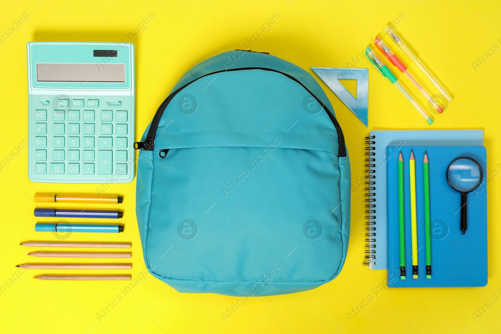 Photo of Light blue backpack and different school supplies on yellow background, flat lay