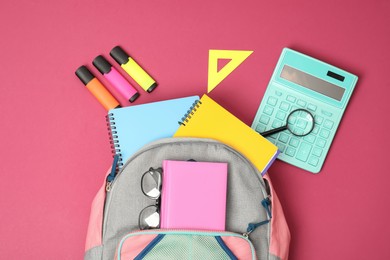 Photo of Backpack and different school supplies on pink background, flat lay